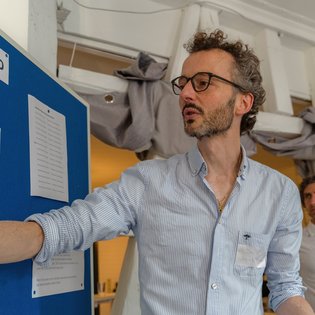 David Studniberg zeigt mit der Hand auf etwas auf einem Flipchart.