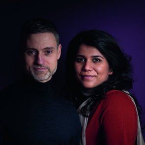 Portrait von Meron Mendel (links) und Saba-Nur Cheema (rechts). Meron Mendel trägt einen dunkelblauen Pulli, hat kurze Haare und einen Bart. Saba-Nur Cheema lehnt sich an seine Seite. Sie hat schwarzes, langes Haar und trägt ein rotes Oberteil.