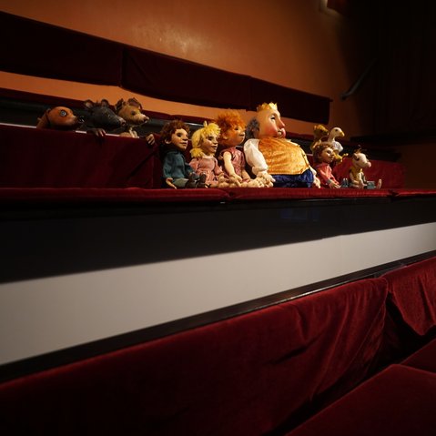Figuren des Theaters sitzen im Zuschauerraum