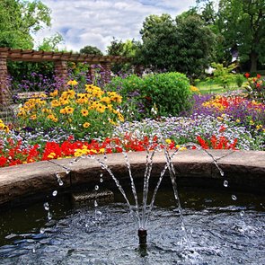 Blick auf einen Springbrunnen und verschiedenfarbig blühende Blumen